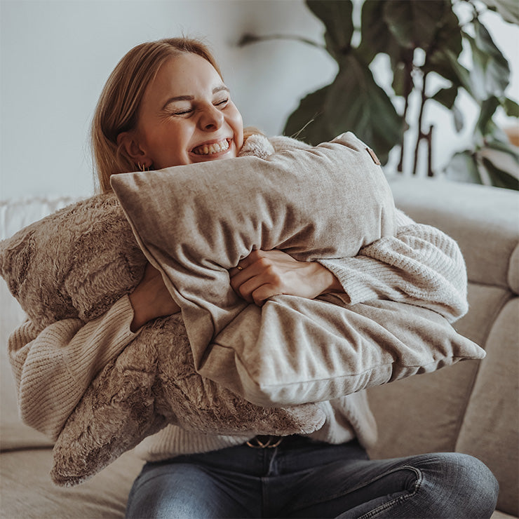 Eine Frau kuschelt sich in weiche Sofakissen von Frau Frauchen