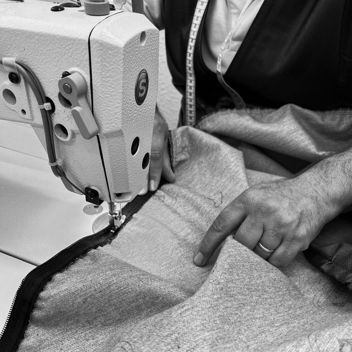 Ein Mann sitzt an einer Nähmaschine und näht ein Hundebett